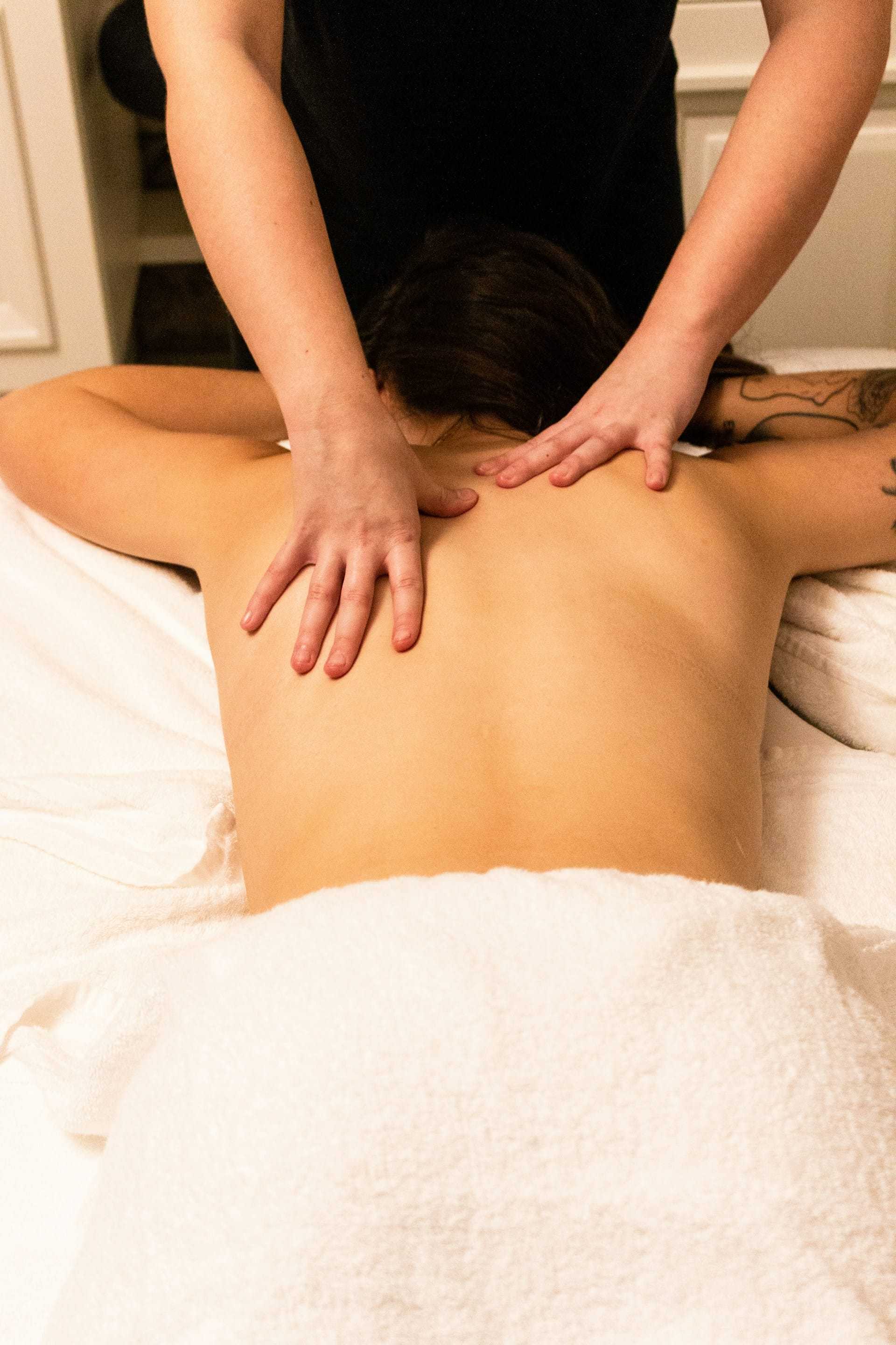 Person receiving a relaxing back massage on a spa table covered with a white towel.