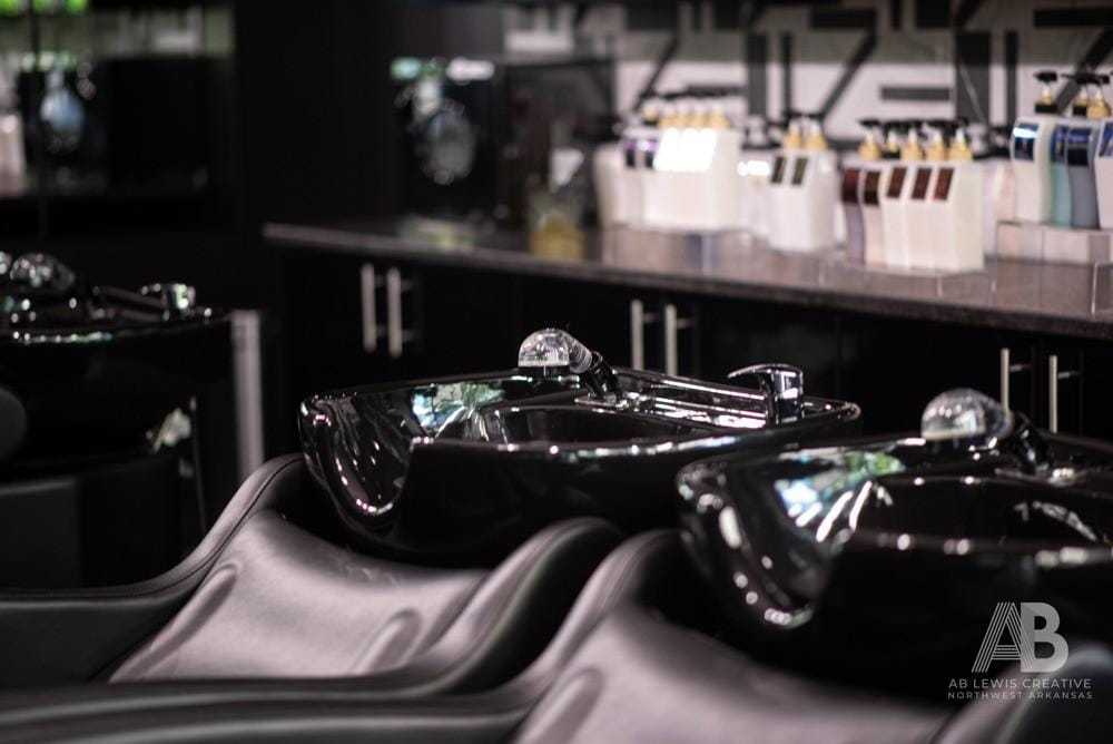 Black salon sinks and chairs in a stylish, modern hair salon setting.